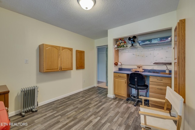 home office featuring dark wood-type flooring, radiator, a textured ceiling, and baseboards