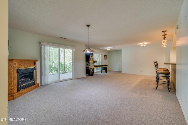 living area featuring carpet floors, visible vents, a glass covered fireplace, a textured ceiling, and baseboards