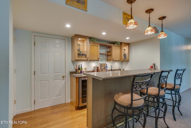 kitchen with a kitchen bar, decorative light fixtures, beverage cooler, kitchen peninsula, and light hardwood / wood-style floors