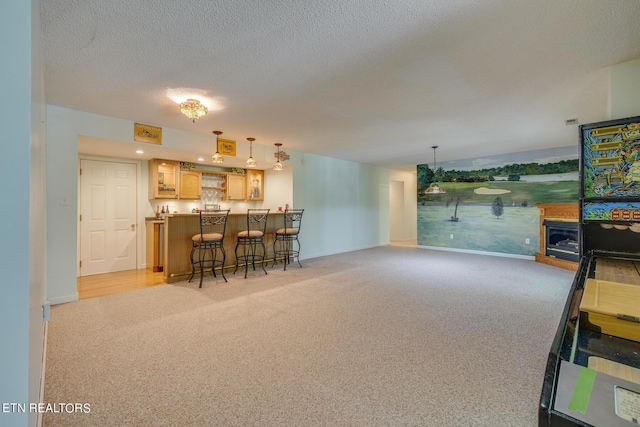 living area featuring light colored carpet, indoor bar, a textured ceiling, and baseboards