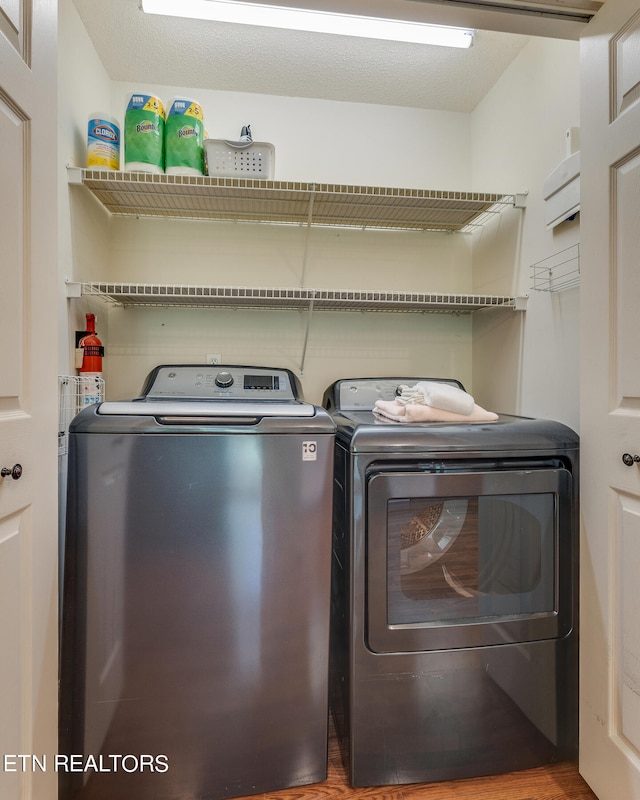 laundry area with wood-type flooring and washing machine and clothes dryer