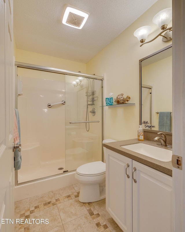 full bath with visible vents, toilet, a stall shower, a textured ceiling, and vanity