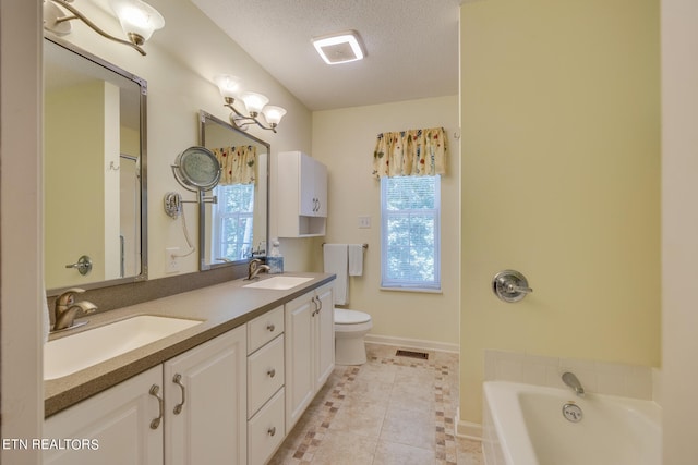 bathroom with a bath, vanity, a wealth of natural light, and a textured ceiling