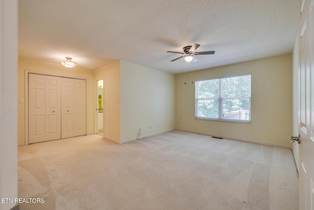 unfurnished room with light colored carpet, visible vents, a ceiling fan, a textured ceiling, and baseboards