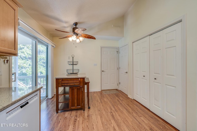 interior space featuring a textured ceiling, light wood finished floors, a ceiling fan, and baseboards