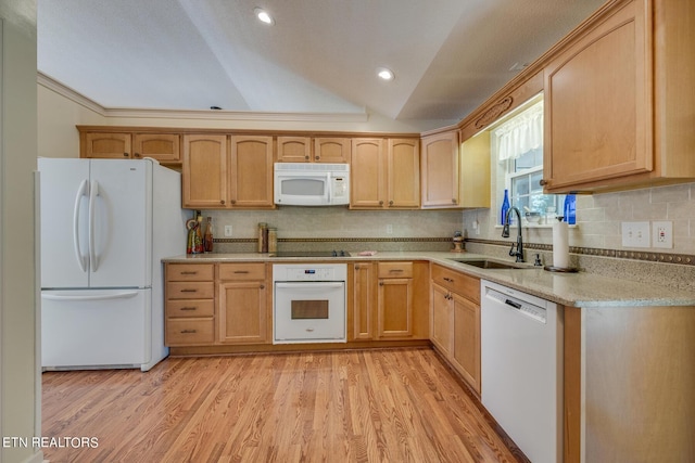 kitchen with lofted ceiling, white appliances, a sink, and light wood-style flooring