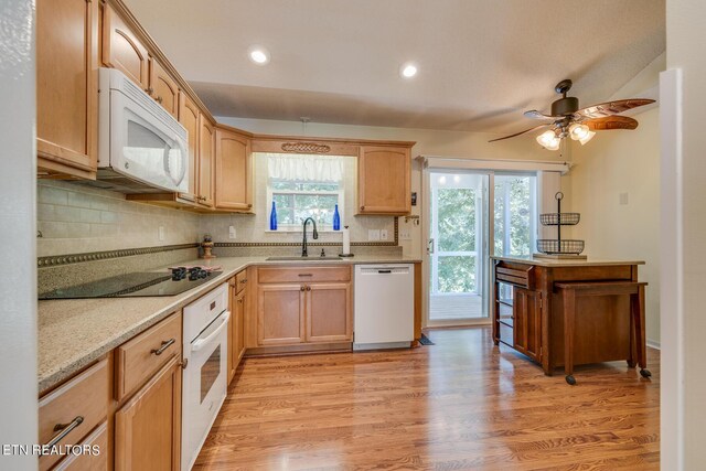 kitchen with white appliances, plenty of natural light, decorative backsplash, and light hardwood / wood-style flooring