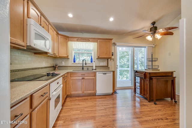 kitchen featuring light wood finished floors, white appliances, backsplash, and a sink