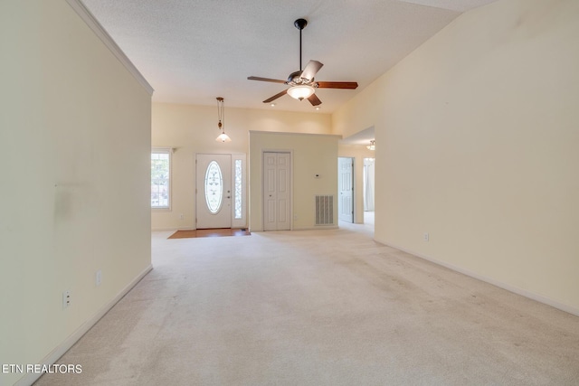 unfurnished living room featuring light colored carpet, visible vents, ceiling fan, a textured ceiling, and high vaulted ceiling