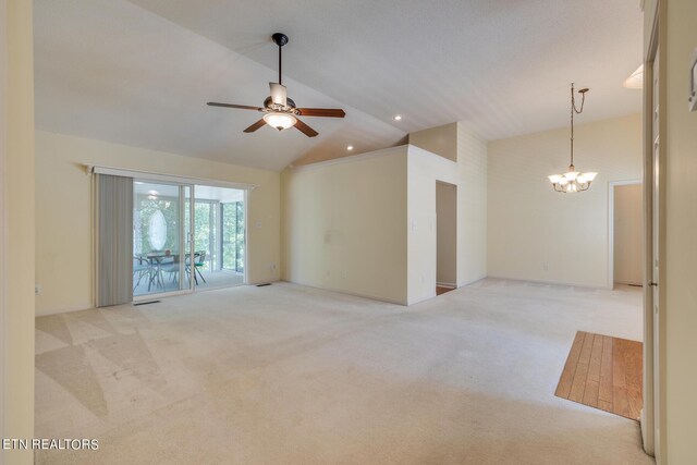 carpeted spare room featuring high vaulted ceiling and ceiling fan with notable chandelier