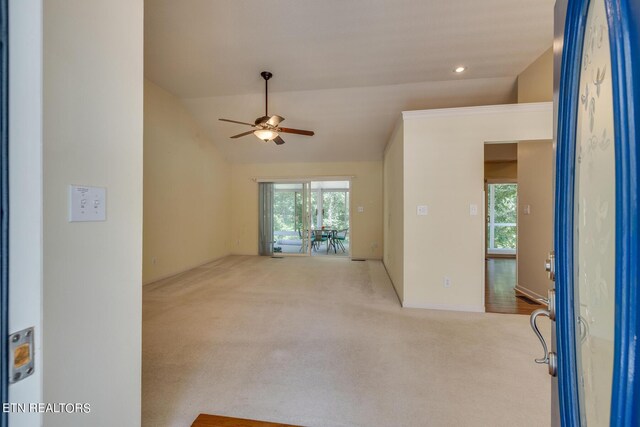 unfurnished living room with light colored carpet, ceiling fan, and vaulted ceiling