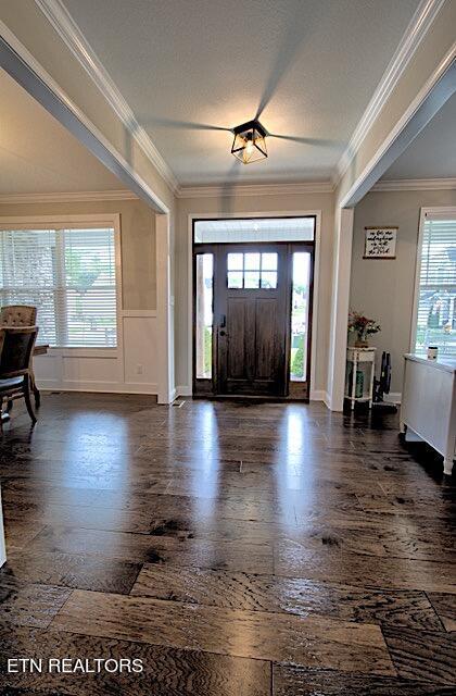 entryway featuring plenty of natural light, dark wood finished floors, and crown molding