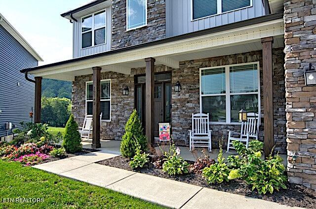 entrance to property featuring board and batten siding, covered porch, and stone siding