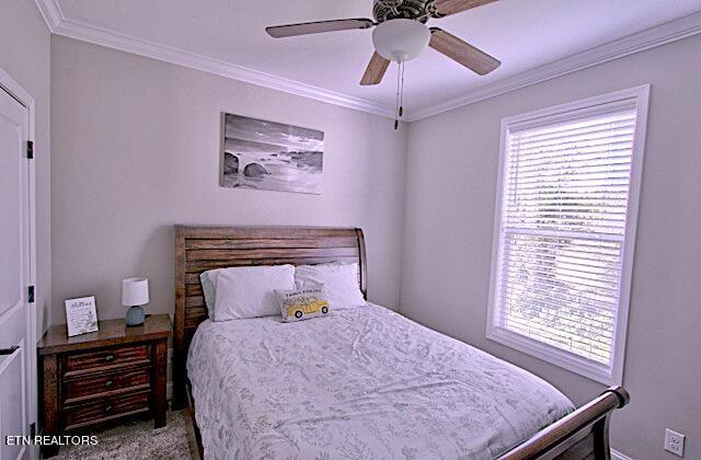 bedroom featuring carpet, ornamental molding, and ceiling fan