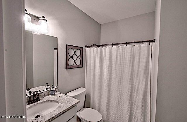 full bath with toilet, a shower with curtain, and vanity