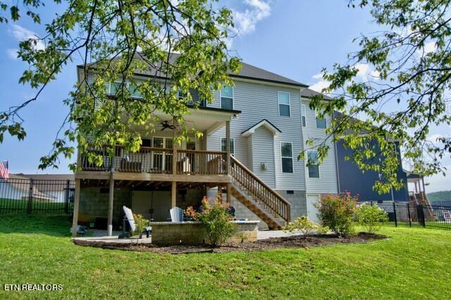 rear view of property with fence, stairway, and a lawn