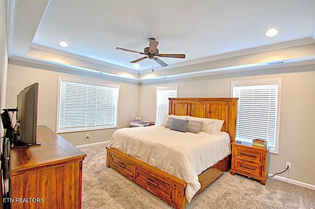 bedroom featuring light carpet, a tray ceiling, and crown molding