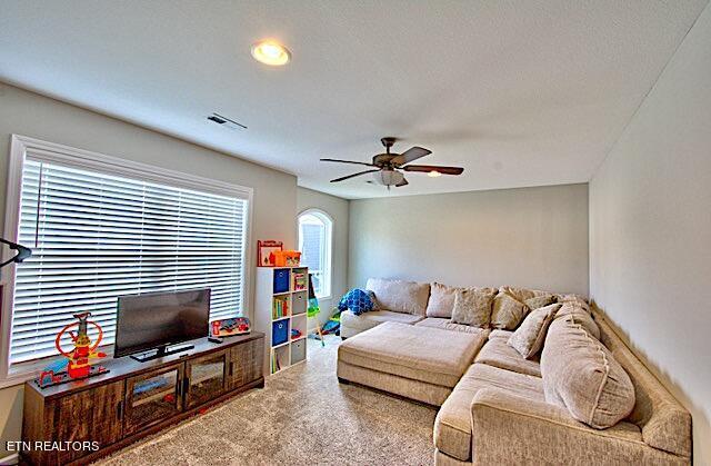 carpeted living room with visible vents and a ceiling fan