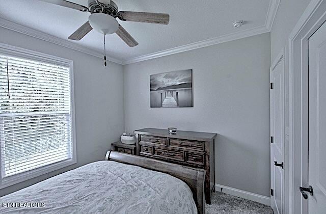 bedroom featuring ornamental molding, light colored carpet, baseboards, and a ceiling fan