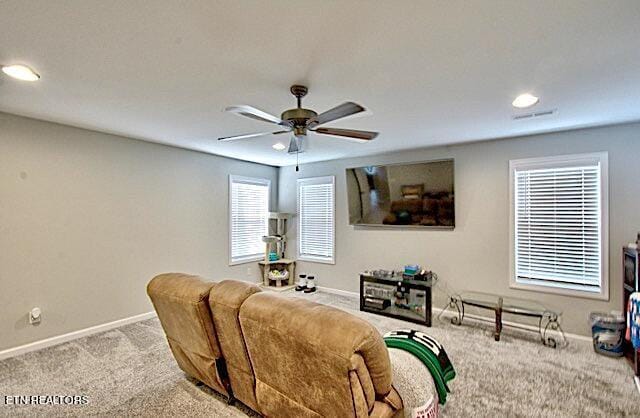 living area with light carpet, ceiling fan, visible vents, and baseboards