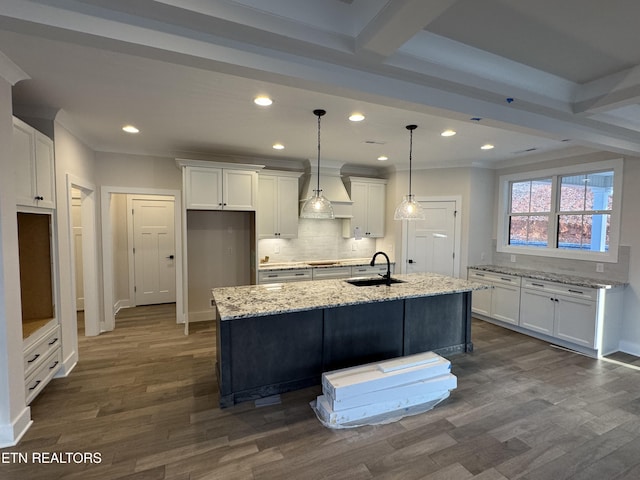 kitchen with sink, white cabinets, backsplash, a kitchen island with sink, and light stone countertops