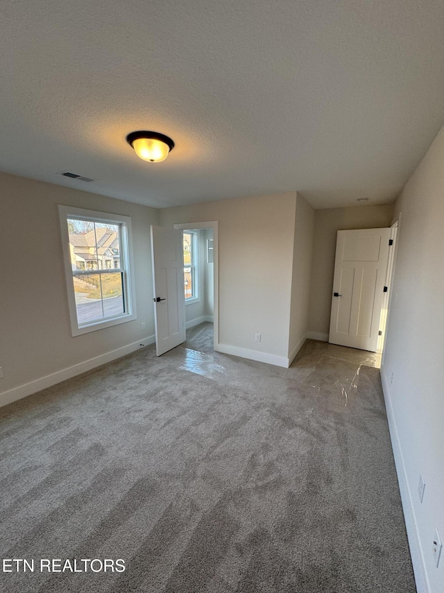 unfurnished room featuring light carpet and a textured ceiling