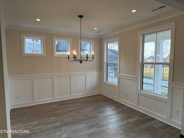 unfurnished dining area featuring ornamental molding, dark hardwood / wood-style floors, and a chandelier