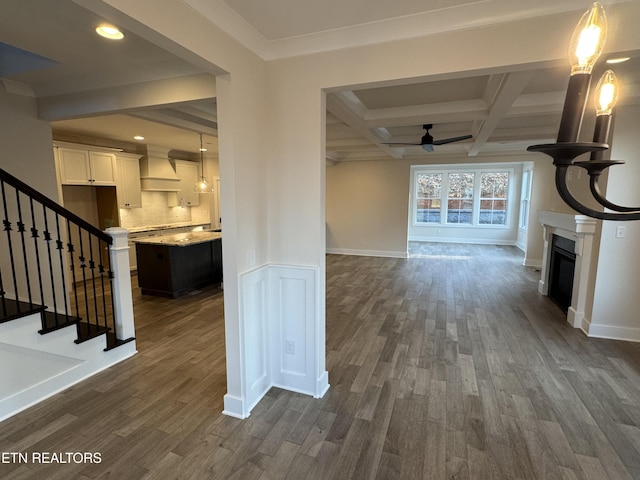 unfurnished living room featuring beamed ceiling, ceiling fan, coffered ceiling, and dark hardwood / wood-style flooring