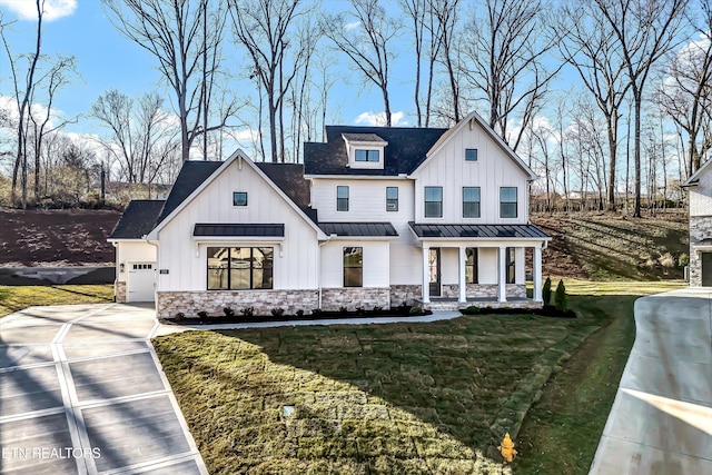 modern inspired farmhouse with board and batten siding, concrete driveway, metal roof, stone siding, and a standing seam roof