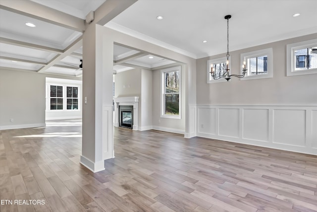 unfurnished dining area with beam ceiling, plenty of natural light, a chandelier, and light wood-style floors