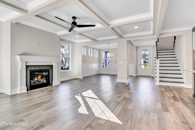 unfurnished living room with a glass covered fireplace, beam ceiling, light wood-style floors, and coffered ceiling