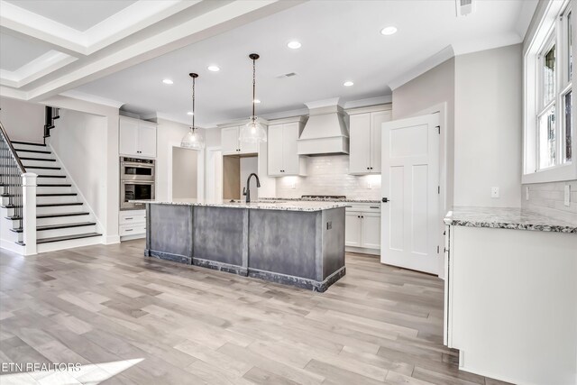 kitchen featuring a sink, light wood-style floors, light stone countertops, and custom exhaust hood