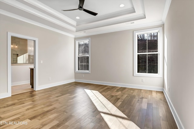 spare room with a tray ceiling, wood finished floors, and ceiling fan