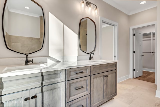 full bath with double vanity, ornamental molding, baseboards, and a sink