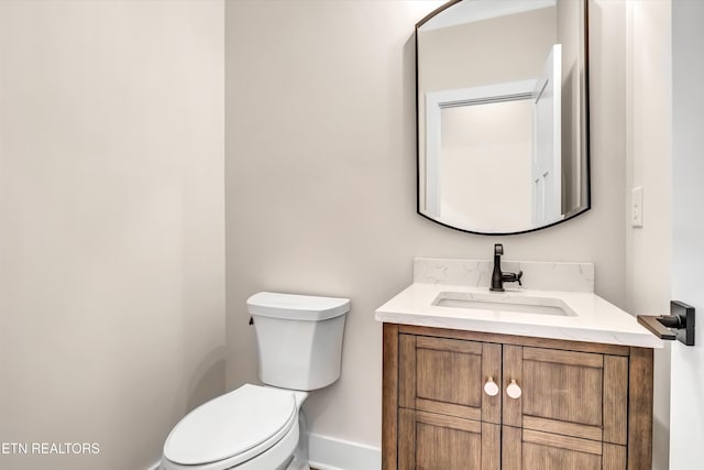 bathroom featuring vanity, toilet, and baseboards