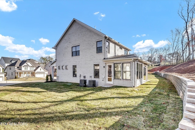 back of house with a lawn, brick siding, and central AC