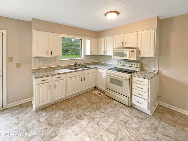 kitchen with light tile patterned flooring, sink, white appliances, and white cabinets