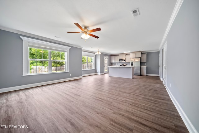 unfurnished living room with ceiling fan, crown molding, plenty of natural light, and dark hardwood / wood-style flooring