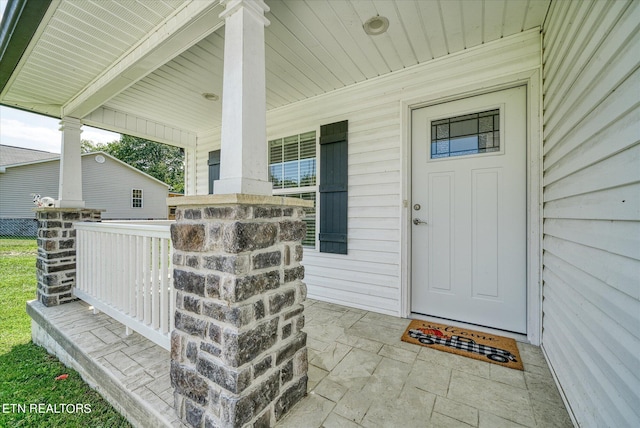 view of exterior entry featuring covered porch