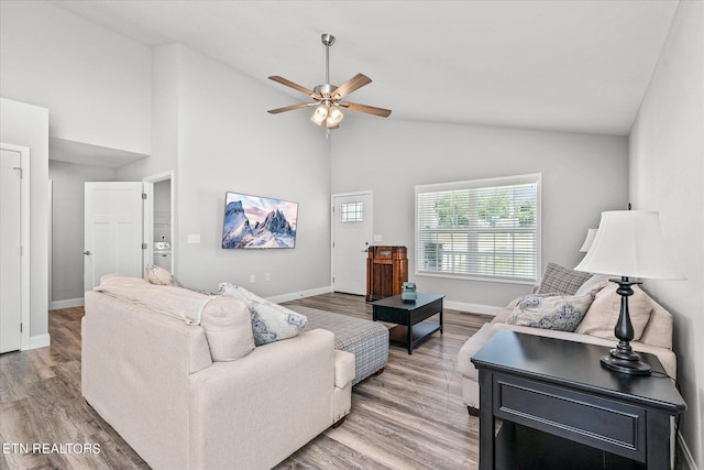 living area featuring high vaulted ceiling, ceiling fan, baseboards, and wood finished floors