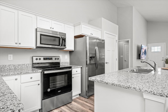 kitchen featuring appliances with stainless steel finishes, white cabinets, a sink, and light stone counters