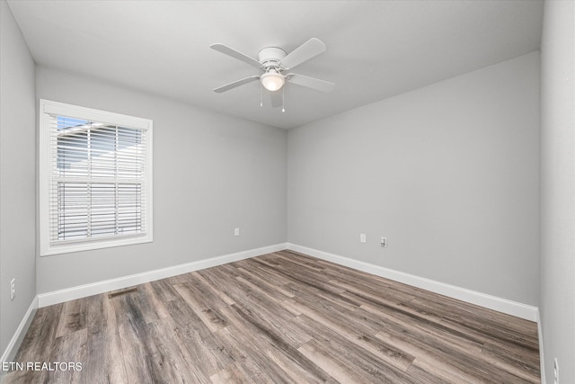 unfurnished room with ceiling fan, wood finished floors, visible vents, and baseboards