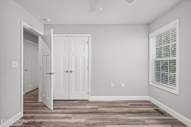 unfurnished bedroom featuring dark wood-style floors, a closet, visible vents, a ceiling fan, and baseboards