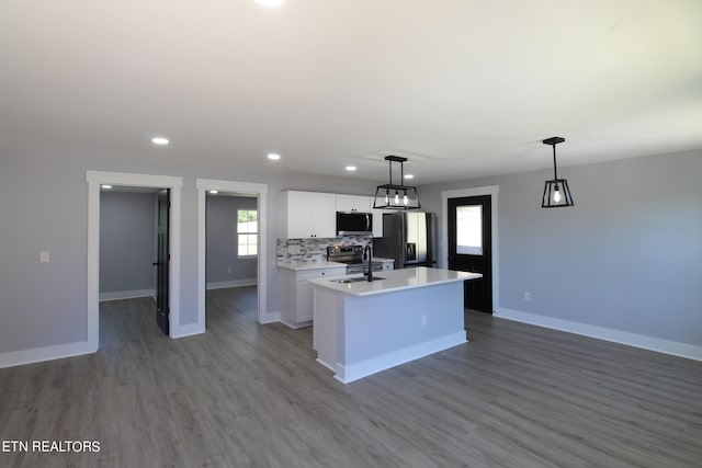 kitchen with appliances with stainless steel finishes, white cabinetry, a center island with sink, wood-type flooring, and hanging light fixtures