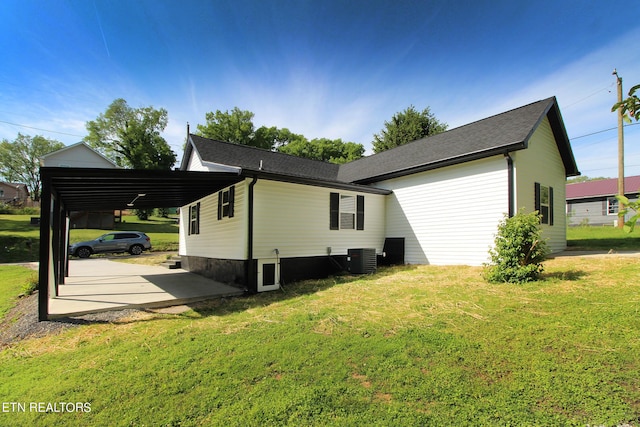 view of side of home with central AC unit, a carport, and a yard