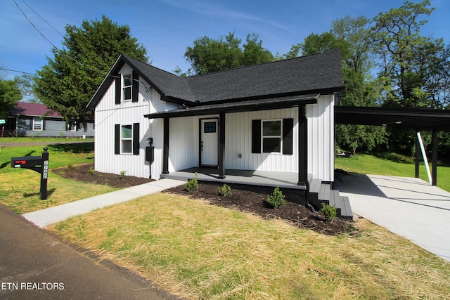 modern farmhouse style home featuring covered porch, an attached carport, roof with shingles, and a front yard