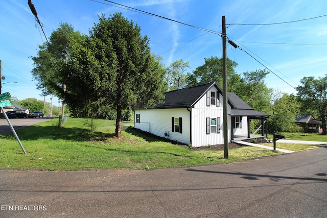 view of side of home featuring roof with shingles and a lawn