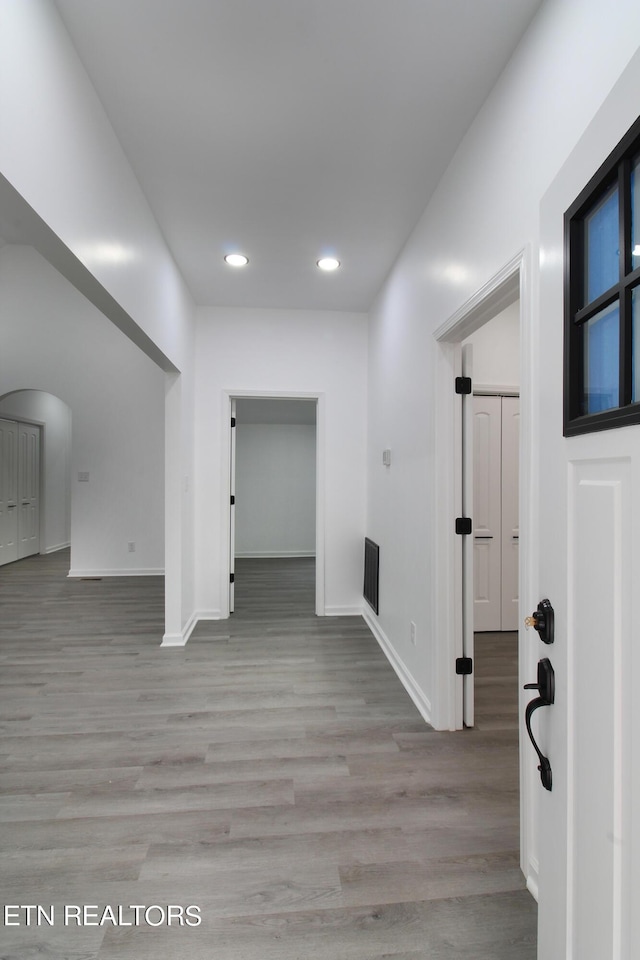 interior space with arched walkways, recessed lighting, wood finished floors, and baseboards