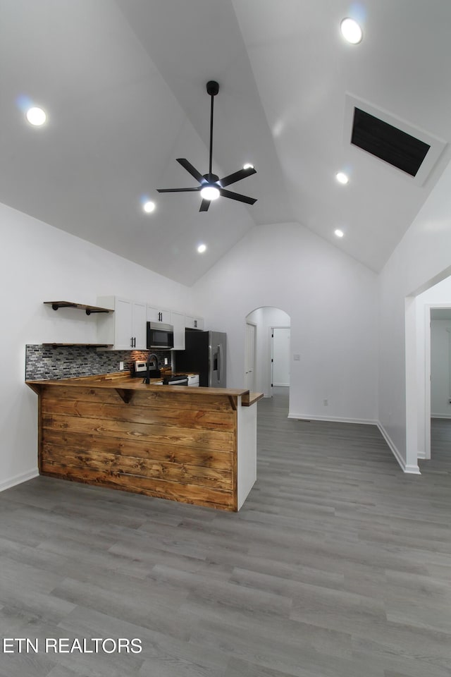 kitchen with arched walkways, ceiling fan, appliances with stainless steel finishes, light wood-style floors, and white cabinetry