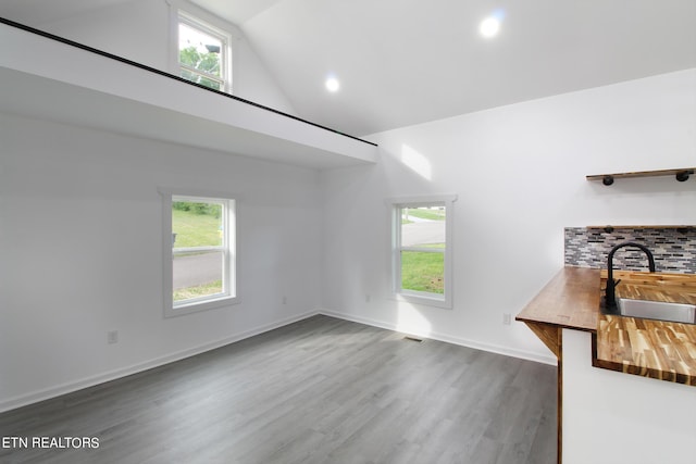 unfurnished living room with plenty of natural light, baseboards, dark wood-type flooring, and a sink